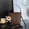 Sac seau marron foncé à texture litchi avec breloque alpaga et plaque dorée élégante - Café Avec Pendentif