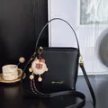 Borsa a secchiello minimalista in pelle nera con logo dorato e ciondolo a forma di orso - nero con ciondolo