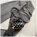 Black polka dot cylinder crossbody bag with a large bow detail and logo on grey blazer - Black