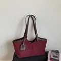 Detail of burgundy suede tote bag showing contrast brown leather straps and metal buckles - Red
