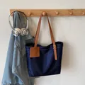 Donkerblauwe waterdichte draagtas met bruine lederen riemen hangend in een huis - Blauw