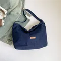 Deep blue denim shoulder bag with brown faux leather label and semi-moon structure - Blue