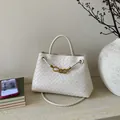 Detailed macro view of white woven leather texture with signature golden knot metal clasp - White