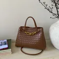 Detail of brown woven leather texture and golden knot hardware on a bucket bag - Brown
