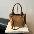Brown suede bucket bag with leather handles and decorative beads on neutral background - Brown with Pendant