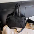 Detail of black nylon tote bag showing metallic rings logo and adjustable strap buckles - Black