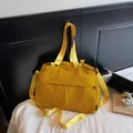 Close-up of vibrant yellow nylon tote bag featuring durable fabric and side brand label - Yellow