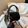 Minimalist black suede crossbody bag with wood bead charm and circular handles - Black
