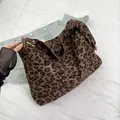 Detail der Leoparden-Einkaufstasche mit braunen Ledergriffen auf Denim-Hintergrund - Braun