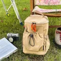 Detail eines khakifarbenen Nylon-Rucksacks mit Kordelzugtaschen in einer Camping-Umgebung - Khaki