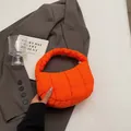 Lebhafte orange gesteppte Puffer-Handtasche auf grauem Anzug, stylische Nylon-Tote - Orange