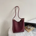 Sac seau chic en cuir bordeaux avec fines bandoulières présenté dans un décor lifestyle - Sans Pendentif / Bordeaux