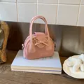 Dettaglio borsa a tracolla rosa con fiocco decorativo e texture scamosciata opaca - Rosa