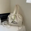 Creamy white nylon tote bag with BANATU logo and cute plush charm in minimalist setting - With Pendant / White