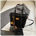 Minimalist black dual-texture bucket bag with gold hardware and plush pompom charm - With Pendant / Black