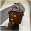 Retro brown bucket bag with contrast stitching and golden hardware charm detail - With Pendant / Coffee