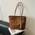 Borsa tote leopardata con ciondolo in peluche e patch in pelle sopra dei libri - Stampa leopardata