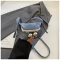 Detail of blue denim mini crossbody bag featuring large silver metal ball clip closure - Denim Blue