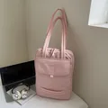 Pink quilted laptop bag with shoulder strap and front pocket on desk with laptop - Pink