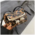Mini-Umhängetasche mit Leopardenmuster und silbernem Kugelverschluss vor grauem Anzug - Leopardenprint