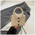 Macro view of shirt-style off-white bag featuring blue buttons and textured leather finish - White