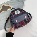 Dettaglio di un mini zaino a quadri con una toppa a forma di orso e patta in pelle blu - Quadri Rossi