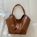 Draufsicht einer braunen Vintage-Beuteltasche mit Glanzfinish auf weichem Stoffhintergrund - Braun