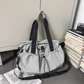 Detail of light grey nylon travel bag with drawstring pocket on minimalist background - Gray