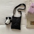 Détail d'un sac bandoulière noir matelassé avec étiquette et breloque pingouin - Noir Avec Pendentif