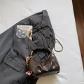 Dark brown pleated faux leather dumpling bag with gold logo and wooden bead charm - Brown