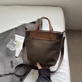 Bolso tote de ante marrón con asas de cuero y correa de tela en un ambiente acogedor - Verde