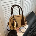 Beige suede small crossbody bag with brown trim and decorative bead pendant - Khaki