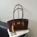 Borsa tote in pelle scamosciata marrone scuro con placca dorata e nappa etnica - Caffè Con Pendente