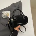 Minimalist black bowling handbag in matte finish with adjustable strap and gold hardware - No Pendant / Black