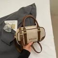 Beige suede bowling bag with brown leather trim and adjustable strap in lifestyle setting - No Pendant / Off White