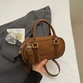 Brown suede bowling bag with leather details and adjustable strap shown in lifestyle setting - No Pendant / Brown