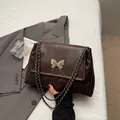 Gewatteerde donkerbruine shopper met vlindersluiting en zilverkleurige kettingriem - koffiekleur