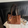 Bruine suède shopper tas met leren riemen en een pluche beer hanger op een wit bed - Bruin met Hanger
