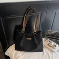 Minimalistische schwarze matte Tragetasche mit braunen Ledergriffen auf weißem Bett - Schwarz ohne Anhänger