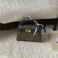 Close-up of brown suede handbag featuring golden twist lock and striped scarf detail - Green