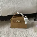 Detail of a brown leather handbag featuring a gold twist lock and a floral silk scarf handle - Brown