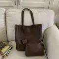 Dettaglio ravvicinato di un set di borse a secchiello marrone scuro in pelle testurizzata - Set Borsa e Pochette / Marrone