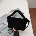 Bolso bandolera minimalista de ante negro con correa ancha sobre fondo de denim - Negro