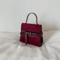 Elegant wine red suede handbag featuring a vintage-style gold buckle and top handle - Red