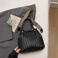 Black woven bucket bag with decorative golden rivets and geometric patterned strap - Black