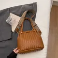 Brown woven leather bucket bag with colorful patterned wide strap on a grey blazer - Tan