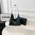 Black glossy pleated hobo bag with matching pouch on white minimalist stand - Black