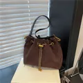 Dark brown suede drawstring bucket bag with gold hardware on a minimalist display stand - Coffee without Pendant