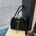 Chic black matte bucket bag with golden chain and drawstring on a minimalist book set - Black without Pendant