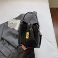 Chic black woven bucket bag with gold twist lock and slim leather shoulder strap - Black